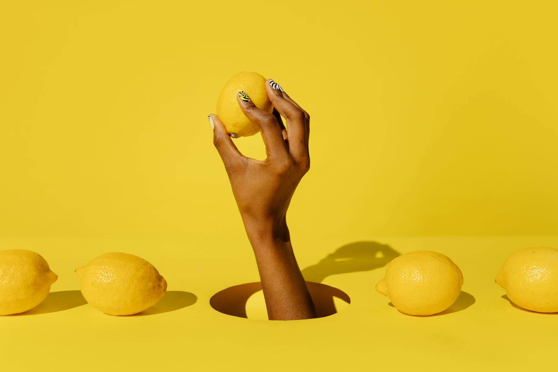 Hand holding a fresh lemon against a vivid yellow background, symbolizing the timing and freshness of peak arousal.
