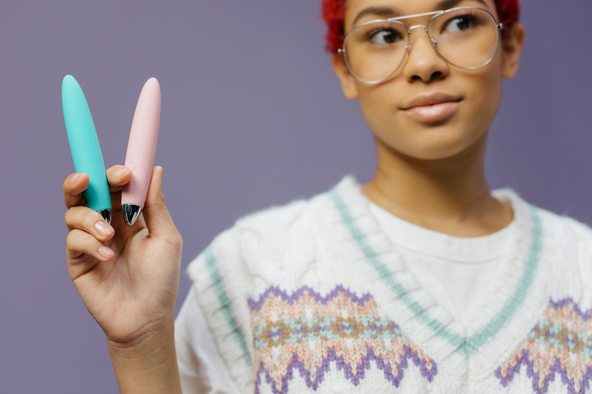 Close-up of hands holding a vibrator against a purple background