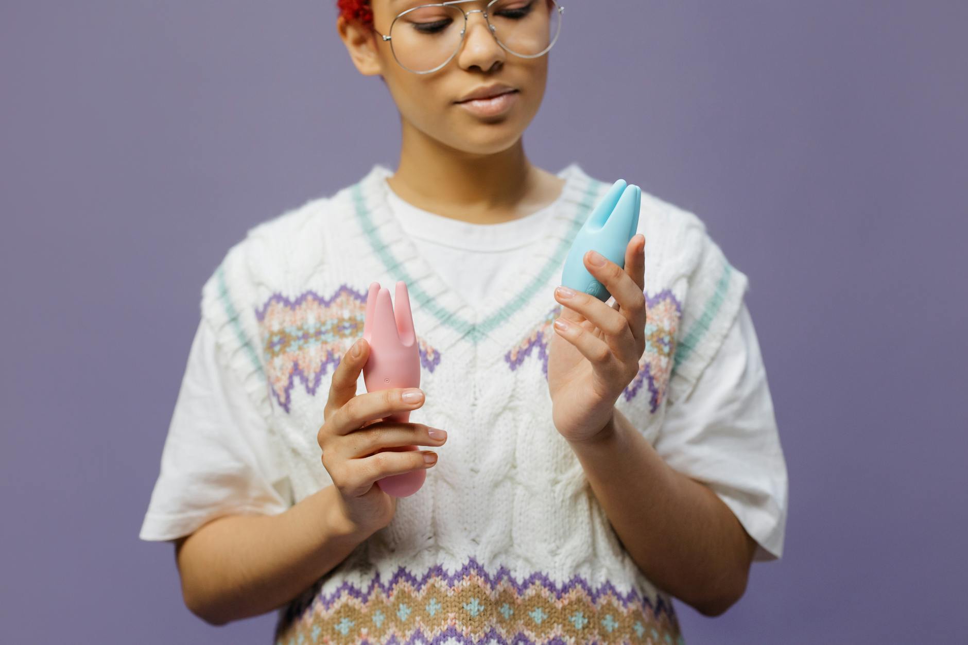 Woman thoughtfully holding silicone vibrators, considering pleasure and healing options.