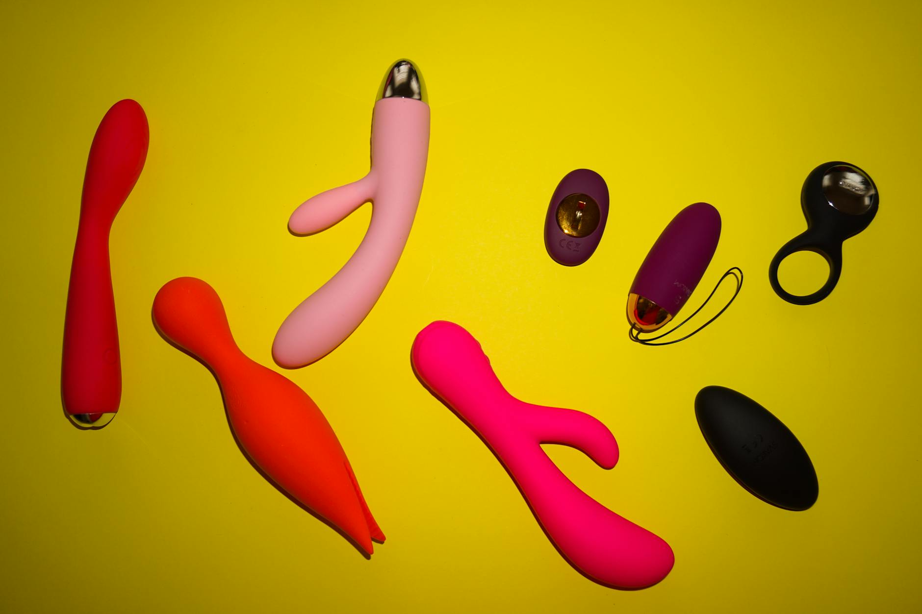 Yellow silicone vibrator surrounded by fresh fruit on a bright yellow background
