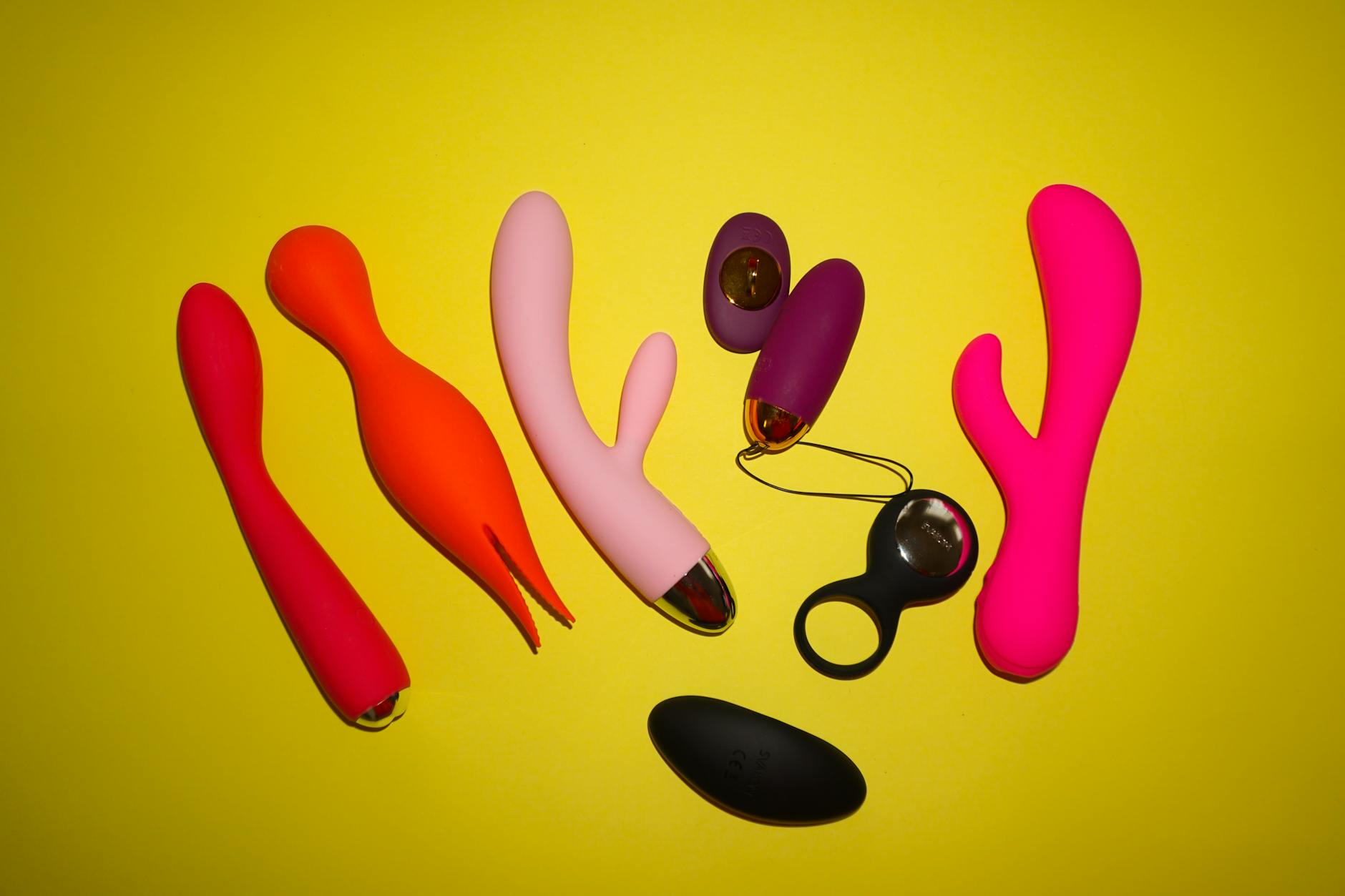 Close-up collection of colorful vibrators and adult toys on a black tray in various shapes and designs